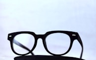 Elegant black-framed glasses placed on a textured white fabric background.