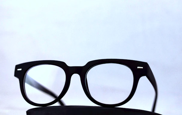 Stylish round eyeglasses displayed on a marble surface with a minimalist background.