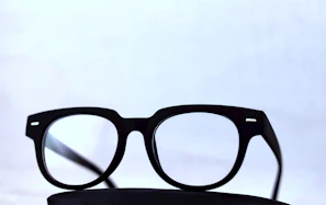 Minimalist clear-frame glasses displayed on a marble surface with soft shadows.