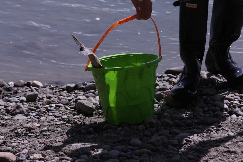 a person standing next to a green bucket