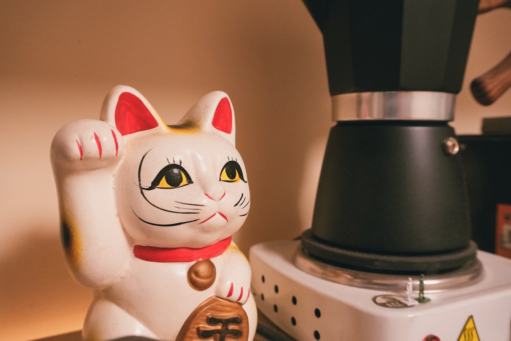 a cat figurine next to a coffee maker