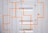 A white corrugated metal door with bright orange, geometric lines and a cross pattern. The door has visible hinges and panels, creating a textured and industrial appearance.