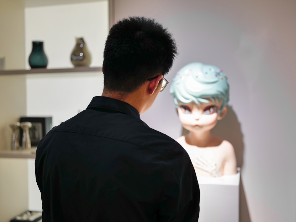 a man standing in front of a display of a mannequin head