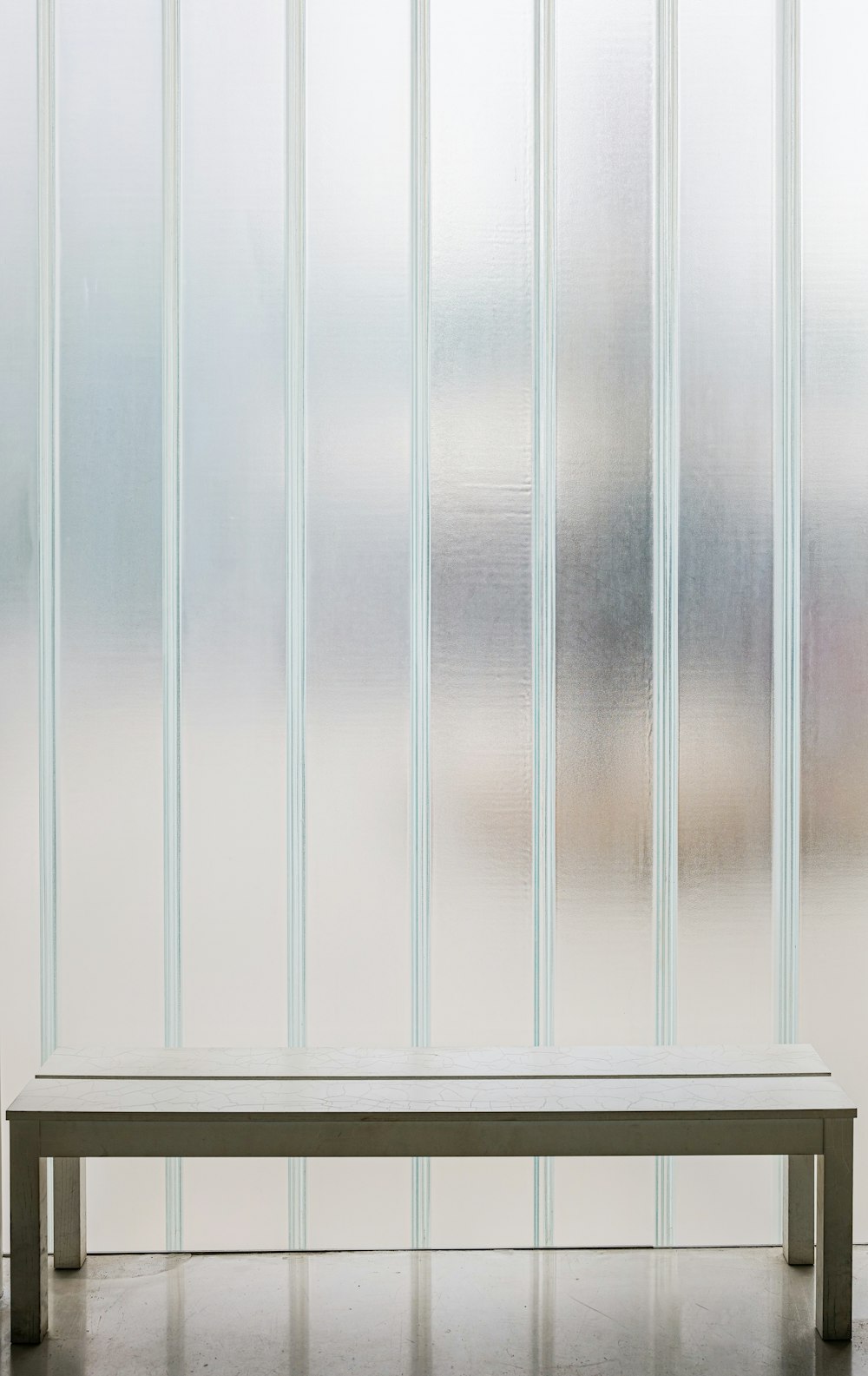 a white bench sitting in front of a window