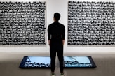 a man standing in front of two paintings