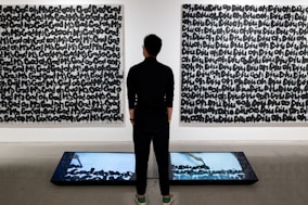 a man standing in front of two paintings
