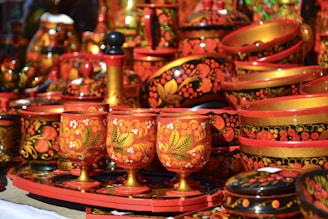 A vibrant set of hand-painted cups displayed on a colorful fabric background.