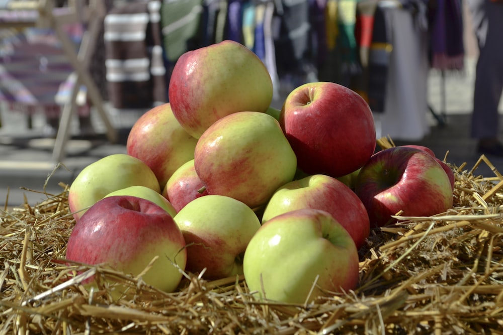 a pile of apples sitting on top of a pile of straw