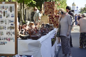 A lively market scene showcasing local pottery and handmade goods under colorful tents.