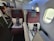A luxurious airplane cabin featuring two burgundy seats with high backs, separated by a partition. Each seat is equipped with a pillow, a blanket, and a package labeled 'B.E.D.D.' The cabin has large windows, allowing natural light to brighten the space. In the aisle, a person and a child can be seen, indicating a comfortable and spacious environment.