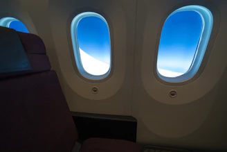 A cozy airplane cabin interior showing comfortable seats and a window view of clouds.