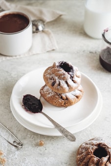 Freshly baked pastries topped with glossy fruit jams displayed on a simple white plate