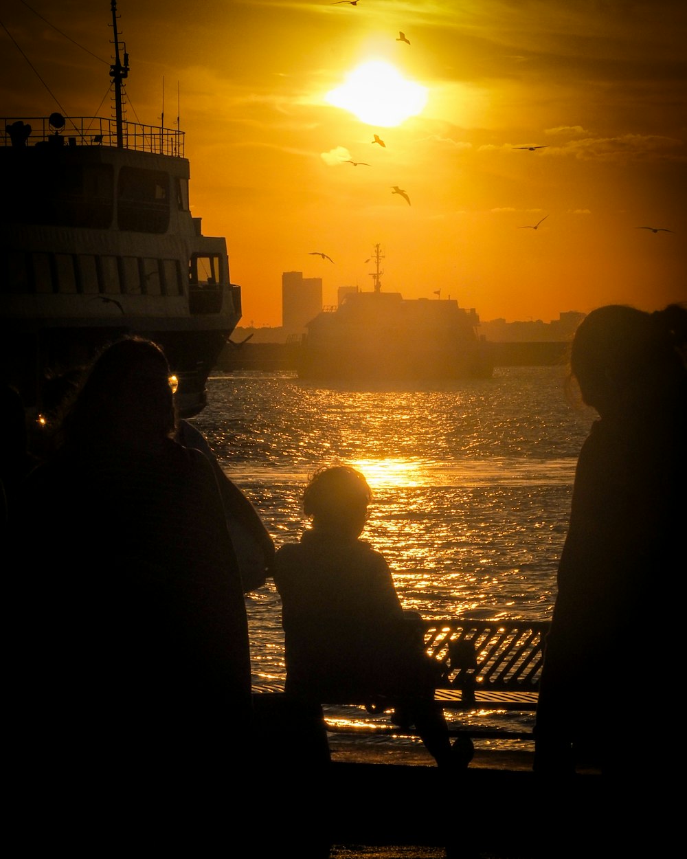 a group of people sitting on a bench watching the sun set