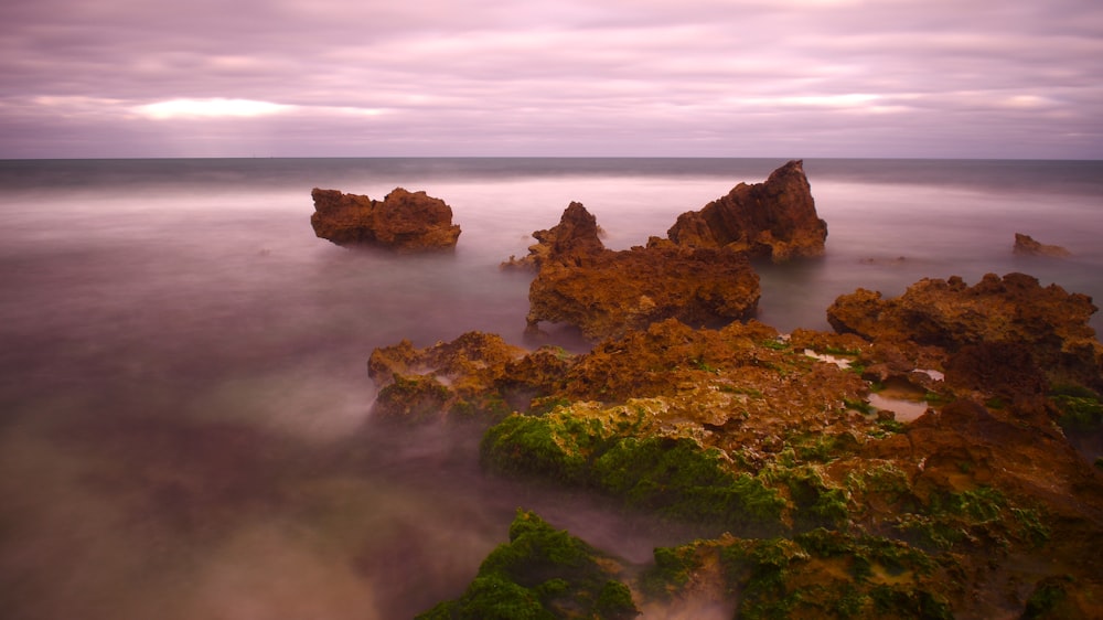 a long exposure of the ocean with rocks in the foreground