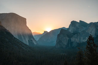 View from the top of a tall cliff overlooking alpine valleys at sunset.