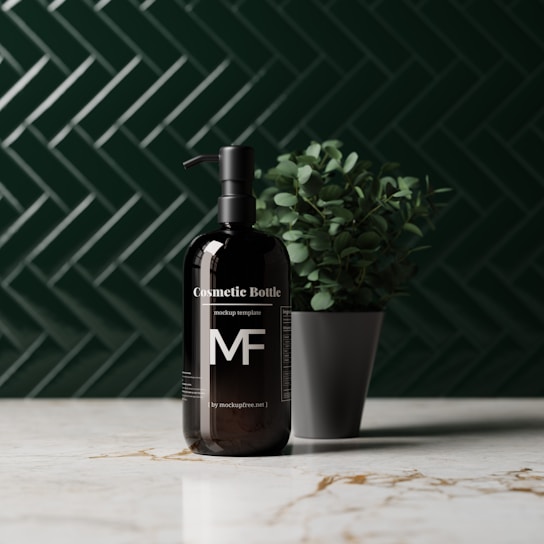 A sleek black cosmetic bottle with a pump sits on a marble countertop. The bottle is labeled with the text 'Cosmetic Bottle' and features the letters 'MF'. It is placed next to a small potted plant with green leaves. The background features a dark green herringbone tile pattern.