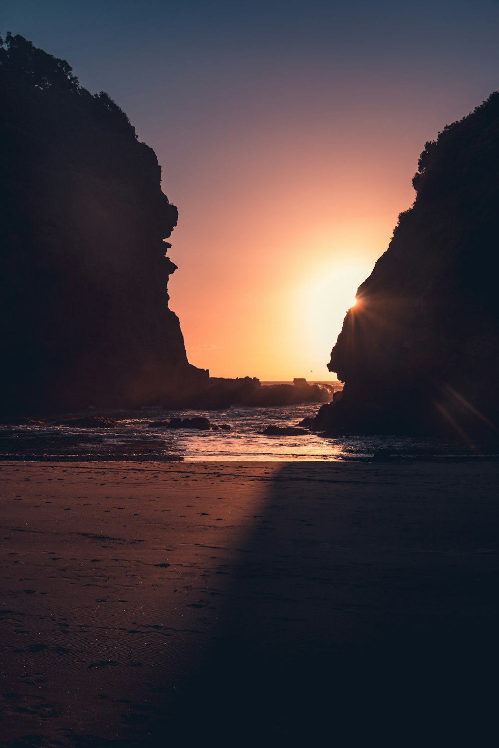 the sun is setting over the water at the beach