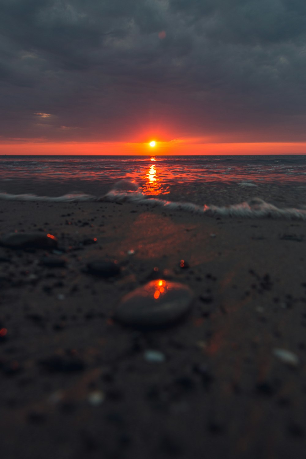 the sun is setting over the water on the beach