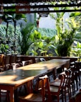 Outdoor dining area with wooden tables and tropical plants