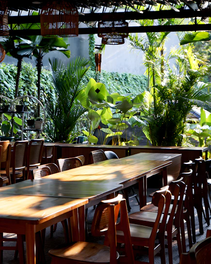 A vibrant tropical outdoor dining area with colorful decor and lush greenery under a bright blue sky.