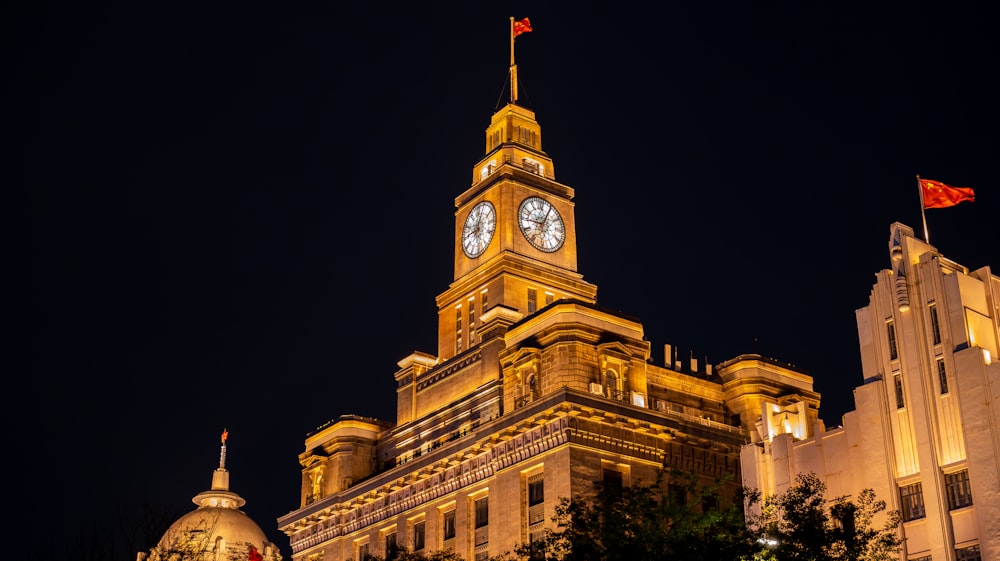 Un grand bâtiment avec une tour de l’horloge la nuit