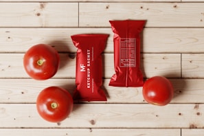 a bag of tomatoes next to three tomatoes on a wooden table
