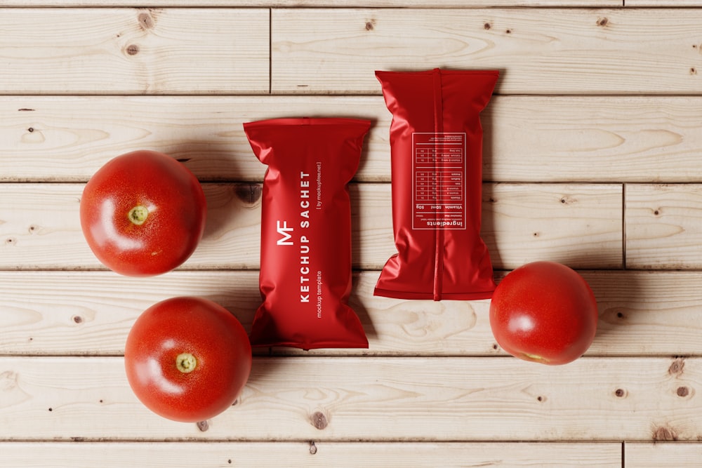 a bag of tomatoes next to three tomatoes on a wooden table