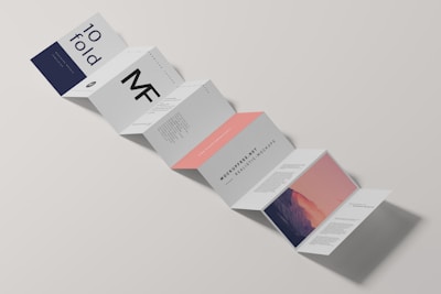 A minimalist design of a folded brochure mockup is displayed against a light background. The sequence of panels shows varied typography and graphics, with a mix of dark blue, white, and peach colors. Some panels contain textual content, while one has an abstract image resembling a mountain with a gradient sky.