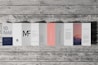 An accordion-style brochure lays open on a wooden surface. The brochure features various panels with text in different fonts and a photograph of a mountain landscape under a pink and purple sky. The text includes large letters, some branding, and mock text representing informational content. One panel is notably a subtle pink color.