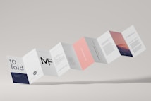 A series of connected rectangular paper flaps arranged in a zigzag pattern, featuring text and imagery. The paper design includes various sections with different colors such as white, navy, pink, and a section with a mountain landscape image. The layout appears professional and modern, with clean typography and minimalistic design elements.