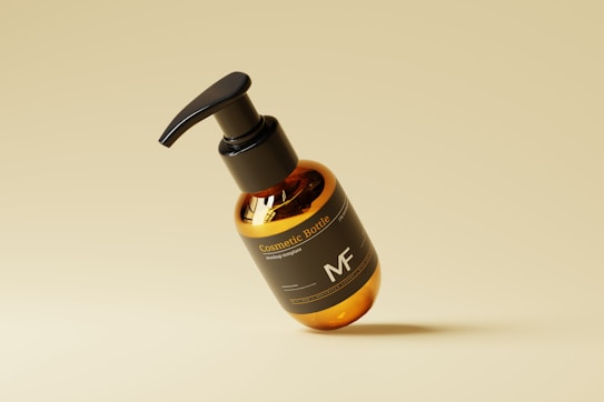 A sleek, amber-colored cosmetic bottle with a black pump lid, labeled 'Cosmetic Bottle' and 'MF', is centrally placed against a minimalist, light tan background. The bottle has a modern design and is slightly tilted, creating a dynamic visual effect.