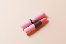 Close-up of a woman applying soft pink lipstick in natural light