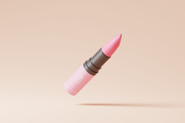 A pink lipstick with a black middle section is depicted against a beige background. The lipstick appears suspended in mid-air with a shadow cast below it.