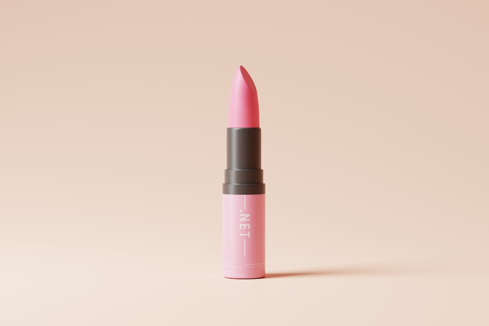 a pink lipstick with a black cap on a beige background
