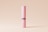 A tall, cylindrical pink container with the label 'MOCKUPFREE.NET' printed vertically in white text. The container has a black band around the middle, and it is placed against a simple, light beige background.