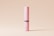 A tall, cylindrical pink container with the label 'MOCKUPFREE.NET' printed vertically in white text. The container has a black band around the middle, and it is placed against a simple, light beige background.