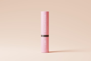 A tall, cylindrical pink container with the label 'MOCKUPFREE.NET' printed vertically in white text. The container has a black band around the middle, and it is placed against a simple, light beige background.