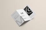 A modern, minimalist trifold brochure mockup that includes clean lines and a monochromatic color scheme. It features text elements and a textured image on one of its panels.