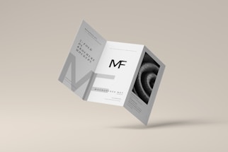 A tri-fold brochure mockup is depicted with a minimalist design. It features clean lines and a modern aesthetic with a grayscale color scheme. The front side has an 'MF' logo, and there's an abstract spiral image on one of the panels.