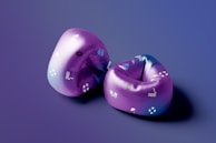 Two purple inflatable swimming sleeves with various small graphics, including flippers, life buoys, and waves, placed on a surface with a smooth gradient background transitioning from a deep purple to blue.