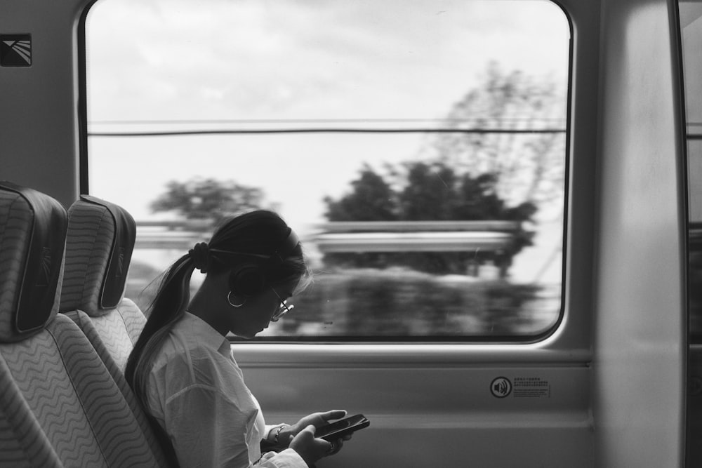 a woman sitting on a train looking at her phone