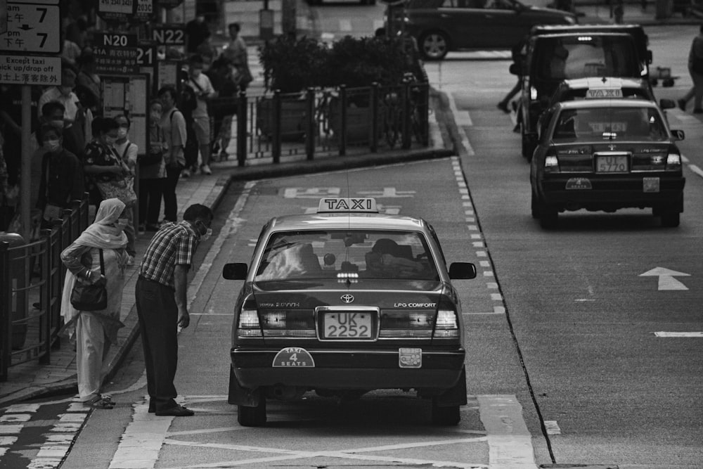 a black and white photo of a taxi cab on a city street