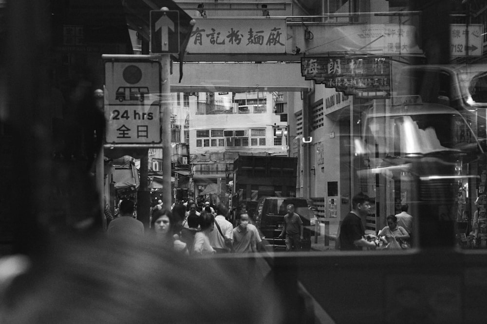 a group of people walking down a street next to tall buildings