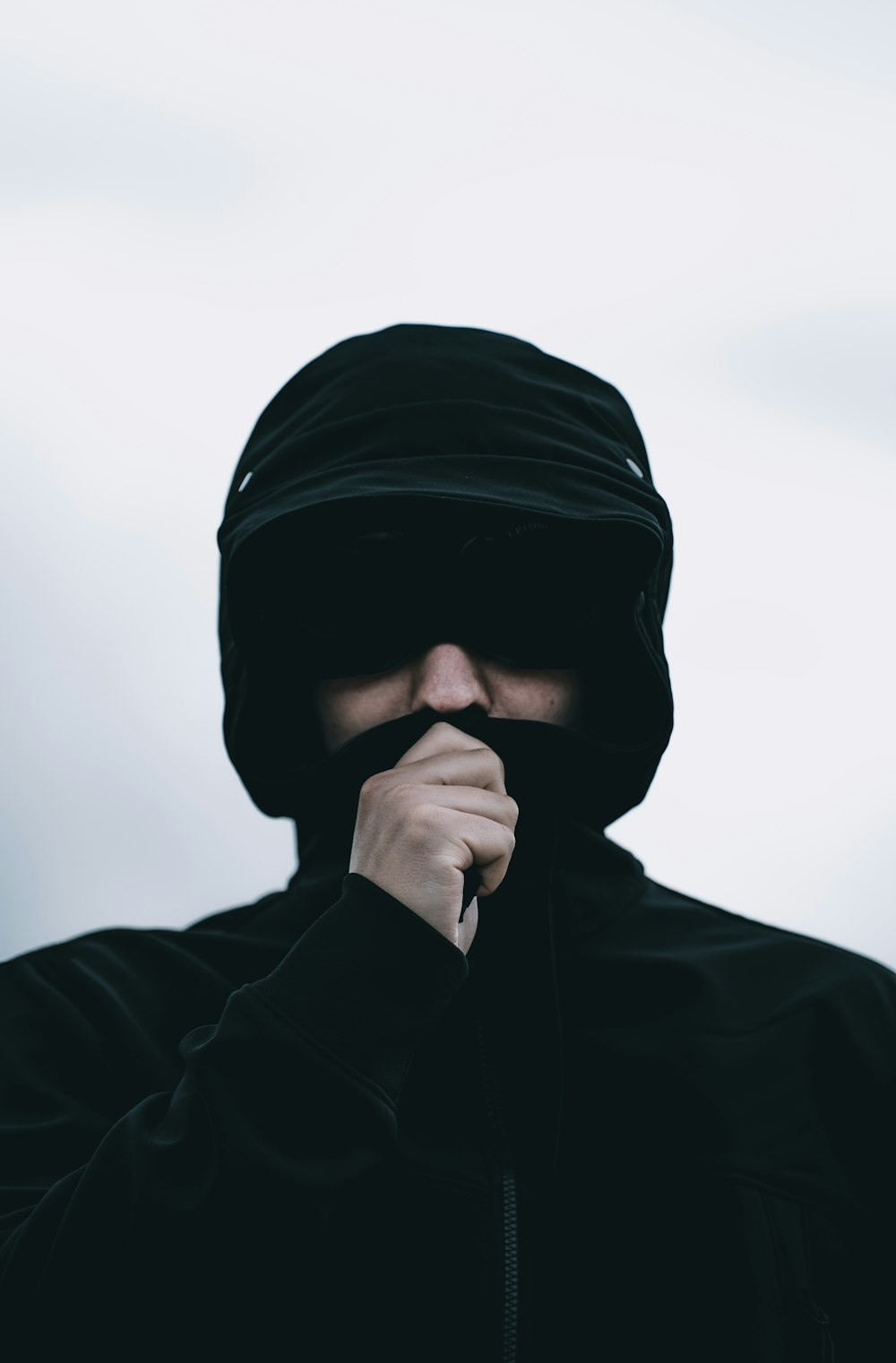 a man wearing a black hoodie and covering his face with his hands