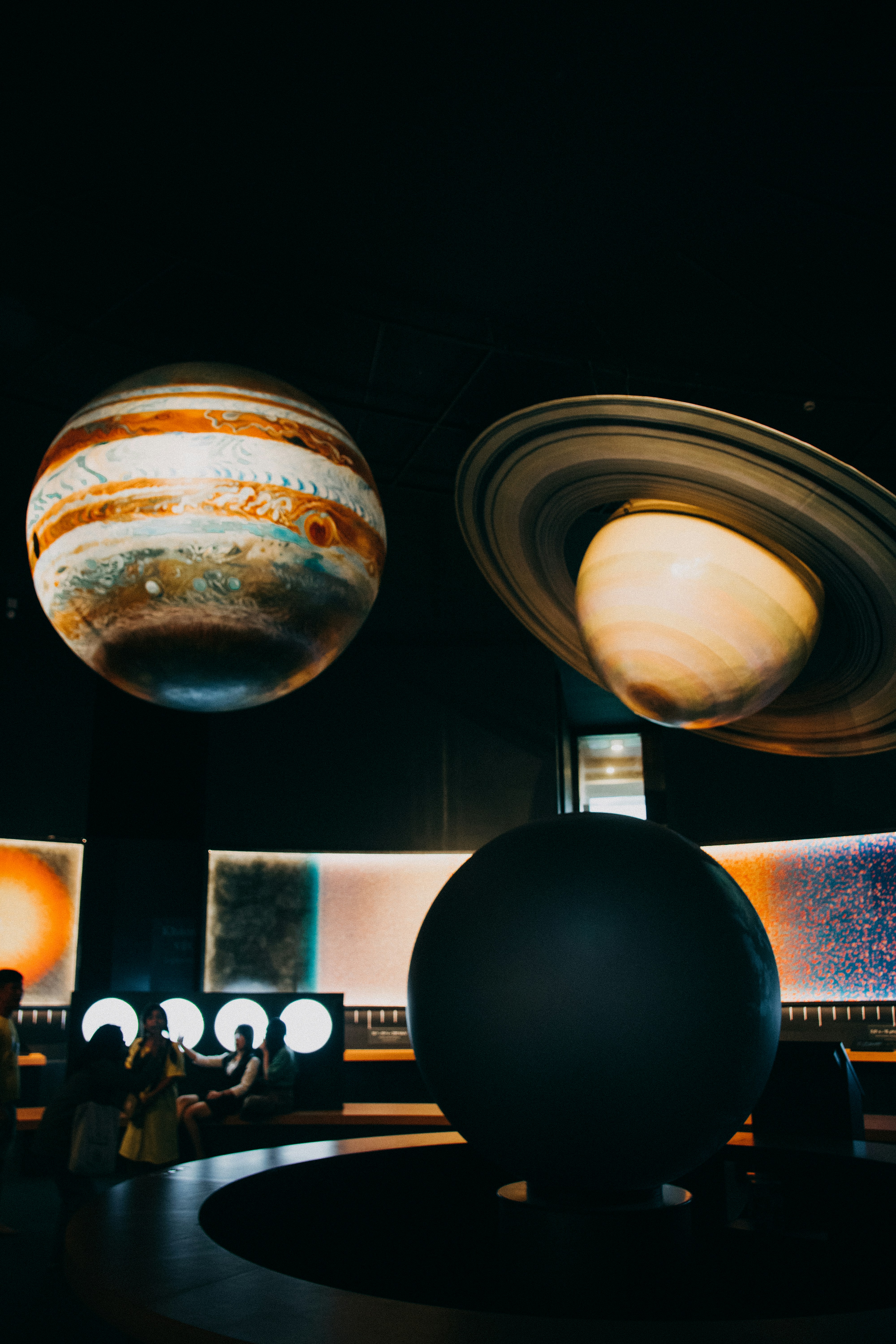 a group of people standing in front of a display of planets