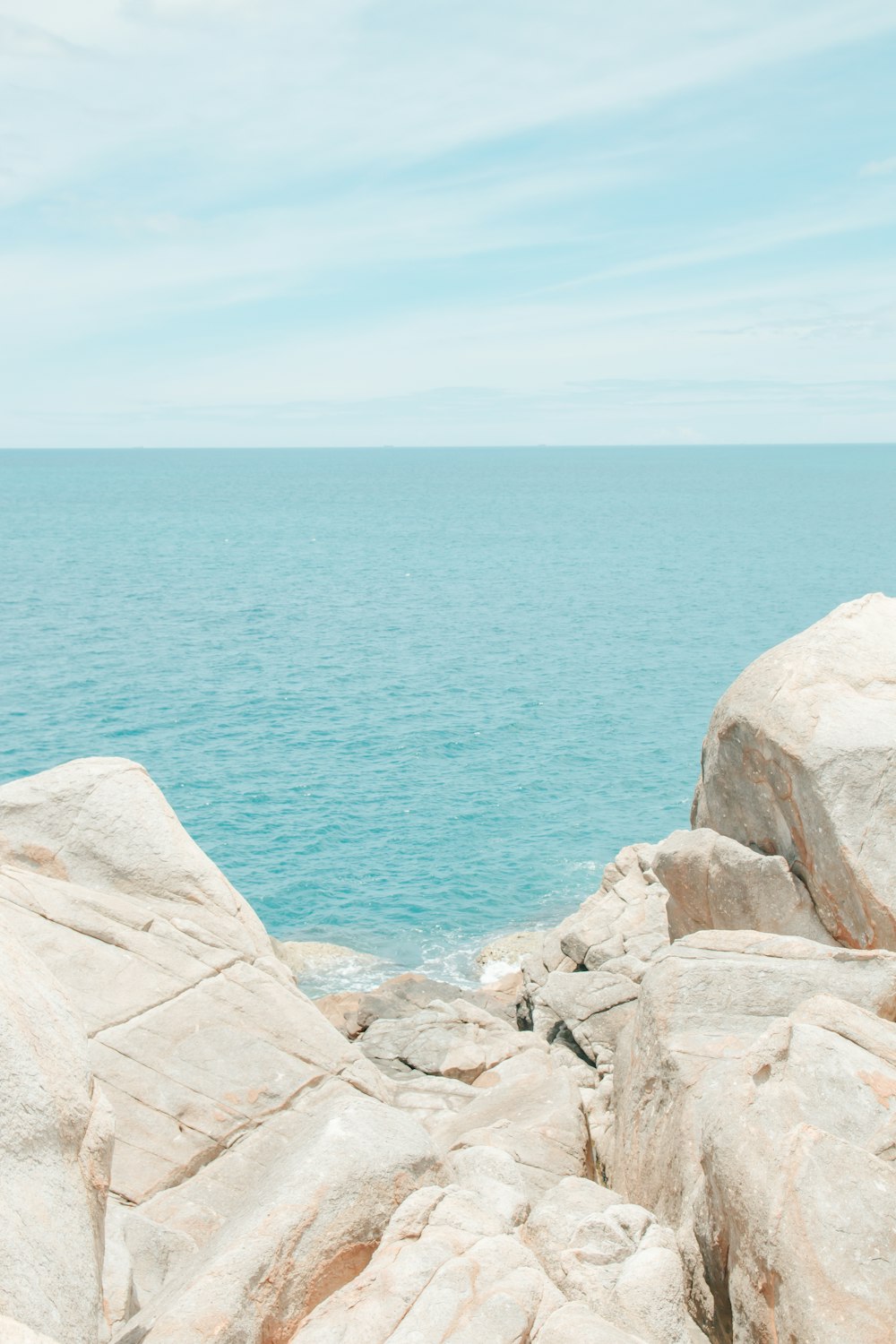 a person sitting on a rock near the ocean