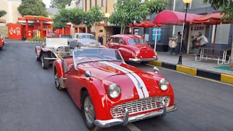 Classic American cars parked near a festive outdoor market showcasing local and American foods.