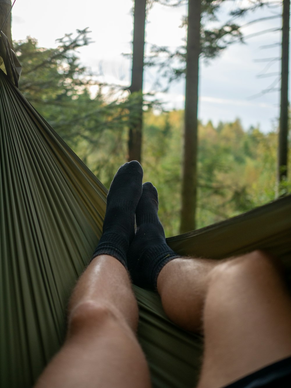 a man laying in a hammock in a forest
