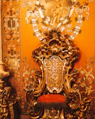 Luxurious black and gold throne chair set against a white backdrop with soft lighting.