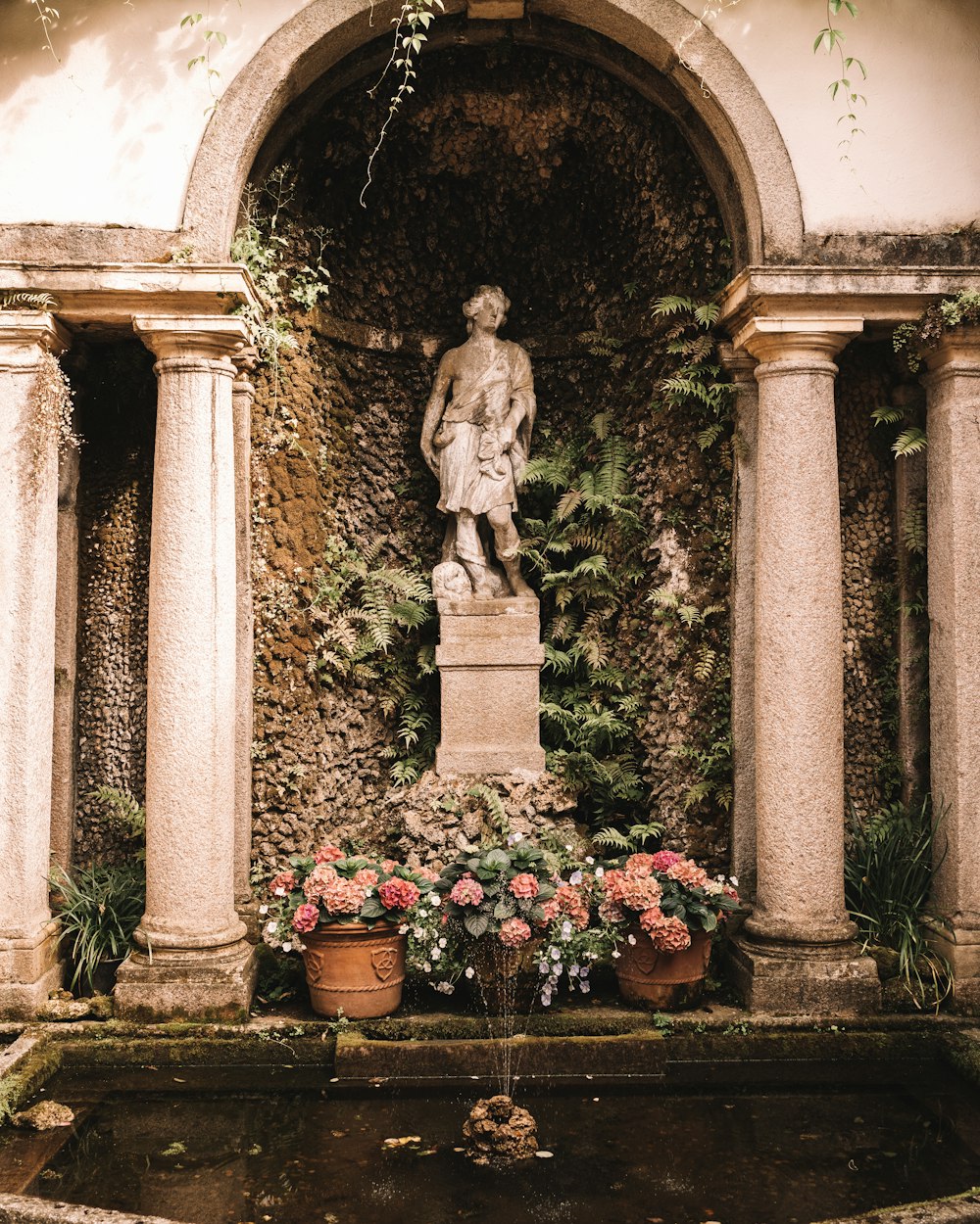 eine Statue eines Mannes, umgeben von Blumen